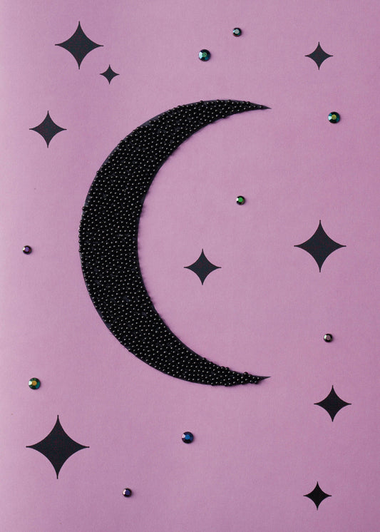 Magical Starry Night Greeting Card, Front of the card showing a crescent moon covered in tiny black beads among black four-point stars and small iridescent gems on a lilac ground.