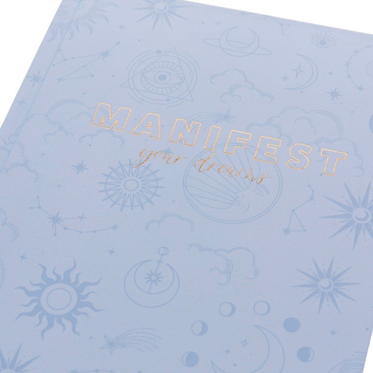 Manifest Self-Care Journal, A periwinkle blue fabric journal printed with celestial suns, moons, and stars under 'Manifest Your Dreams' in gold foil.