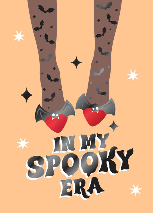My Spooky Era Greeting Card, Front of the card showing legs in bat-and-star tights and red heart-shaped bat shoes on a peach ground above the words IN MY SPOOKY ERA.