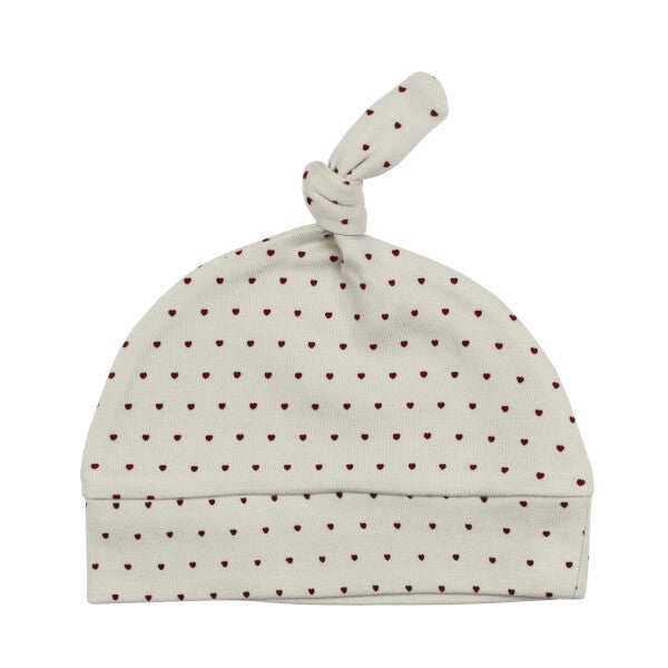Organic Knotted Baby Hat, Crimson Mini Hearts, A cream colored knotted baby hat covered in small crimson heart print with a top knot detail.