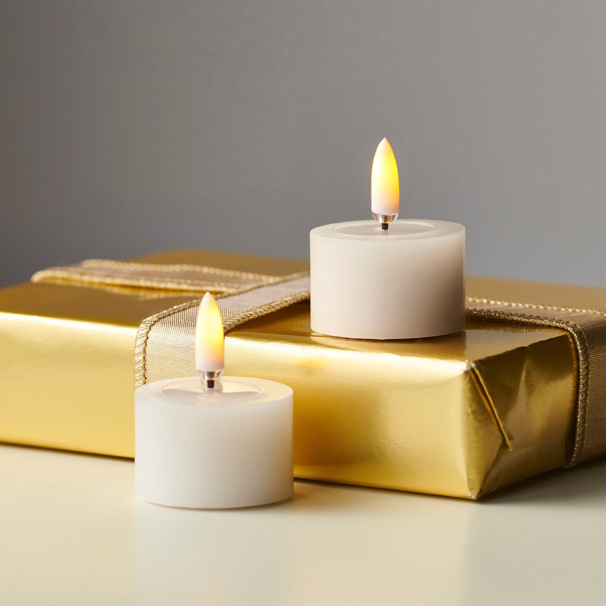 Pair of Ivory Melted Top Flameless Tealights, Two ivory flameless tealights with melted wax tops and lit flame-shaped tips, side by side on a white background.