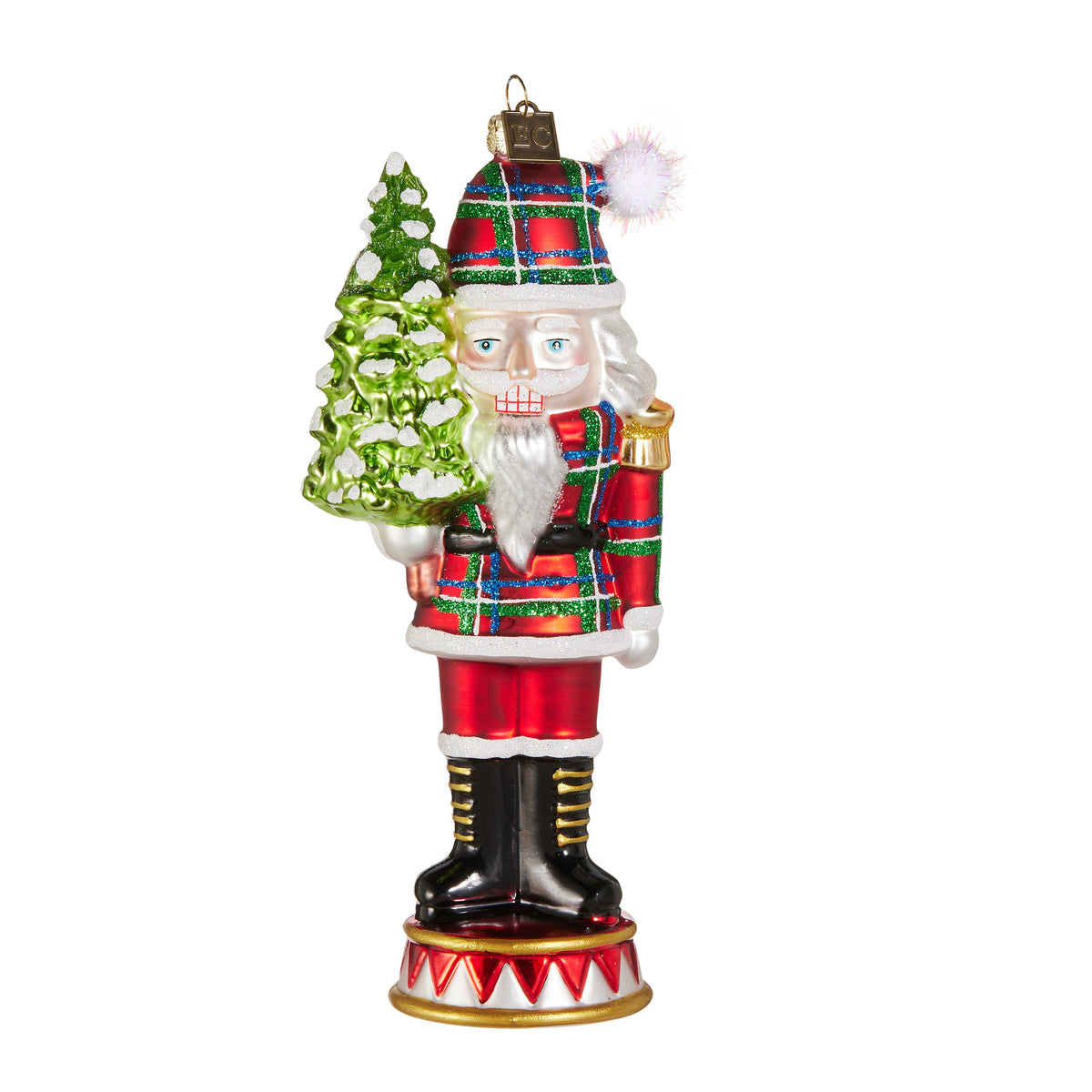 Plaid Nutcracker Ornament, A glass nutcracker ornament dressed in red, green and blue plaid, holding a snow covered tree.