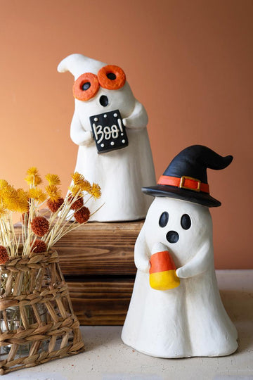 Resin Halloween Ghost, Two white resin ghost figures on a wooden crate, one wearing round orange glasses and holding a black BOO sign, the other wearing a black witch hat and holding a candy corn.