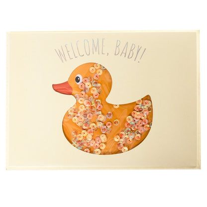 Rubber Ducky Baby Handmade Card, A cream card with a die-cut duck shape filled with iridescent sequins and Welcome, Baby! in holographic foil, shown with its envelope.