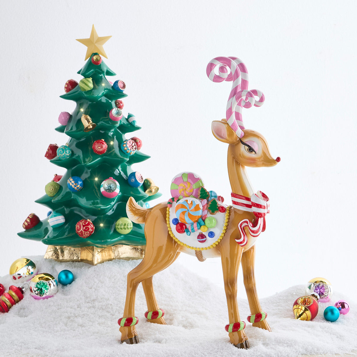 Sassy Jingle Standing Deer Figure with Candy Cane Antlers, A brown resin deer standing on four legs with pink and white candy cane antlers, a red and white striped bow and a white saddle piled with candy.