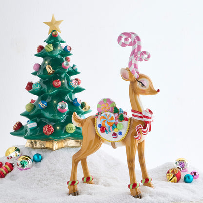 Sassy Jingle Standing Deer Figure with Candy Cane Antlers, A brown resin deer standing on four legs with pink and white candy cane antlers, a red and white striped bow and a white saddle piled with candy.