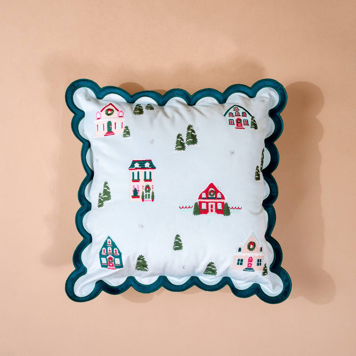 Scalloped Square Throw Pillow, A light blue square throw pillow embroidered with a snowy village of small cottages and trees, edged in a teal scalloped trim.