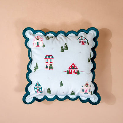 Scalloped Square Throw Pillow, A light blue square throw pillow embroidered with a snowy village of small cottages and trees, edged in a teal scalloped trim.