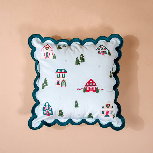 Scalloped Square Throw Pillow, A light blue square throw pillow embroidered with a snowy village of small cottages and trees, edged in a teal scalloped trim.