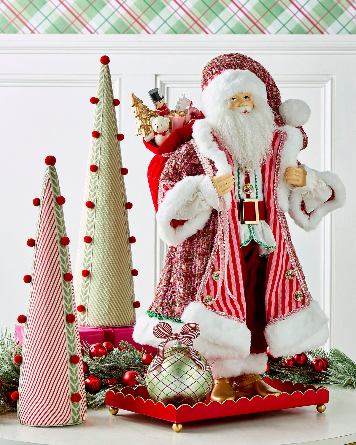Sugar and Spice Santa, A large Santa figure in a pink and red striped coat with white fur trim, gold boots, and a jeweled belt, carrying a sack of toys over one shoulder.