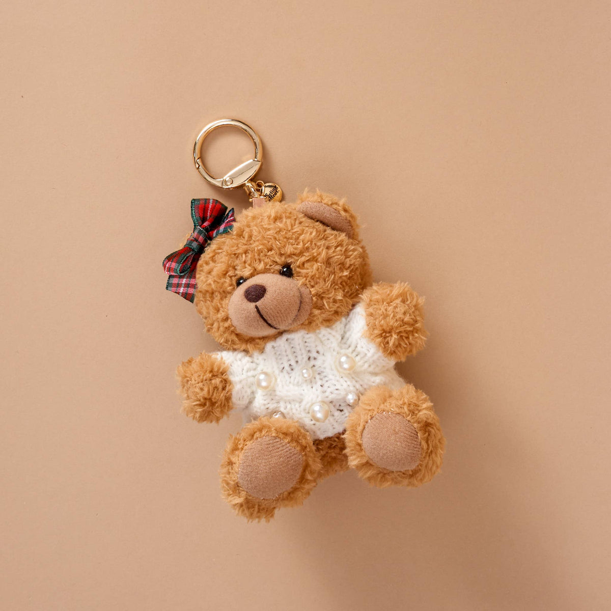 Teddy Bear Bag Charm, A golden brown plush teddy bear bag charm dressed in a black and white football jersey, holding a football, with a gold clasp.