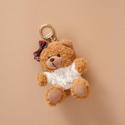 Teddy Bear Bag Charm, A golden brown plush teddy bear bag charm dressed in a black and white football jersey, holding a football, with a gold clasp.
