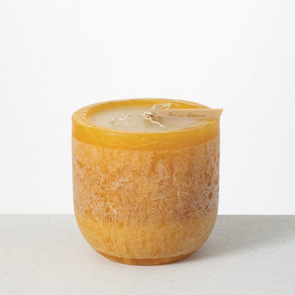Timber Goblet Candle 6 x 6 Inch, A round, cup-shaped candle in golden amber wax with a mottled, bark-like surface, a wide cream wax top holding a looped wick, and a wooden tag reading Vance Kitira resting across the rim.