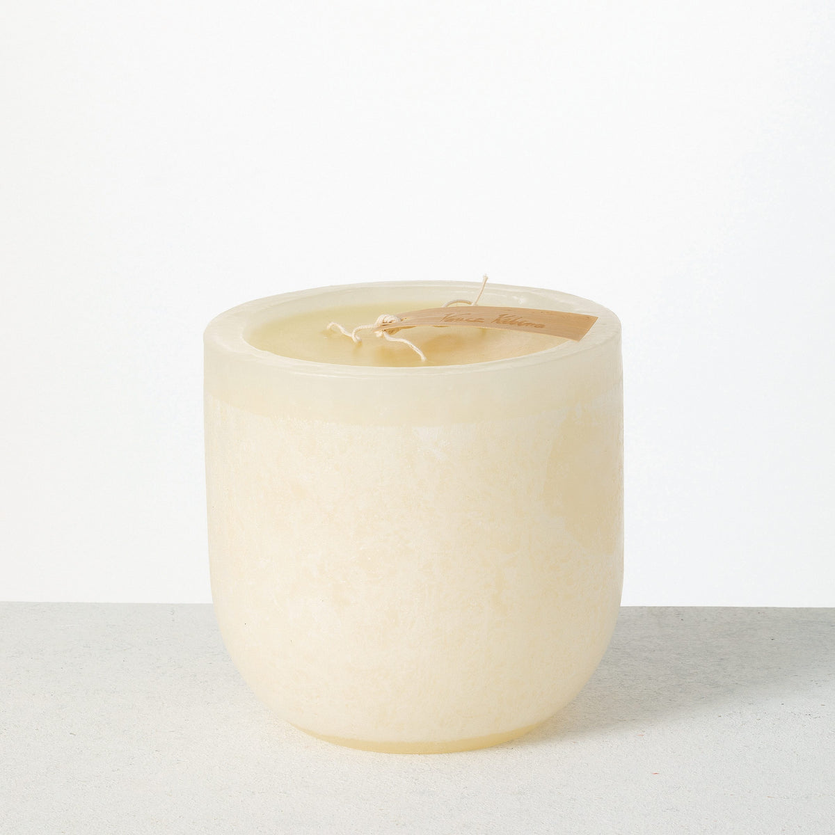 Timber Goblet Candle 6 x 6 Inch, A round, cup-shaped candle in golden amber wax with a mottled, bark-like surface, a wide cream wax top holding a looped wick, and a wooden tag reading Vance Kitira resting across the rim.