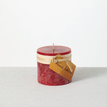 Timber Pillar Candle 3.25 x 3 Inch, A short pillar candle in warm honey gold sits on a plain background with a cream band and a paper tag around its middle.