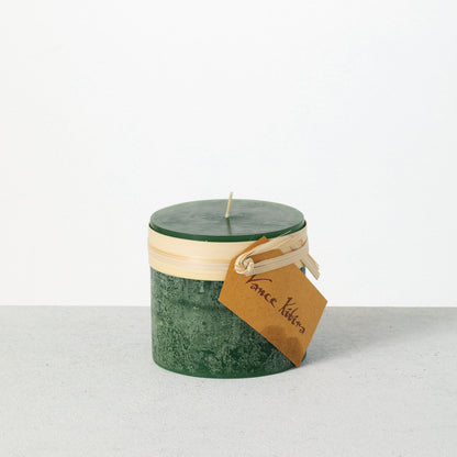 Timber Pillar Candle 3.25 x 3 Inch, A short pillar candle in warm honey gold sits on a plain background with a cream band and a paper tag around its middle.
