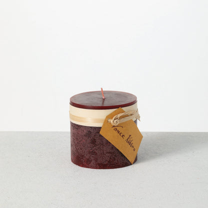 Timber Pillar Candle 3.25 x 3 Inch, A short pillar candle in warm honey gold sits on a plain background with a cream band and a paper tag around its middle.