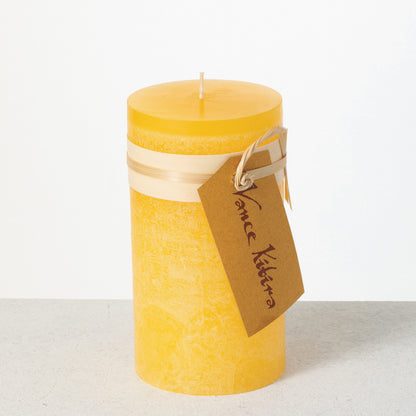 Timber Pillar Candle 3.25 x 6 Inch, A tall reddish brown pillar candle with a textured surface stands tied with a paper band and a hang tag.