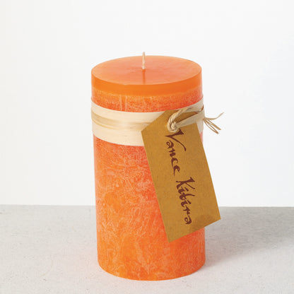 Timber Pillar Candle 3.25 x 6 Inch, A tall reddish brown pillar candle with a textured surface stands tied with a paper band and a hang tag.