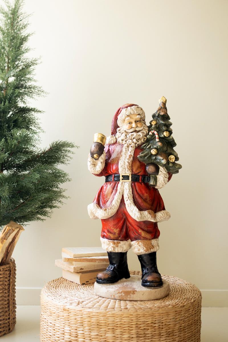 Traditional Faux Concrete Santa with Bell, A tall faux concrete Santa figure in a red suit holding a small Christmas tree.