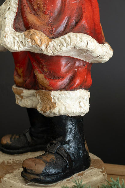 Traditional Faux Concrete Santa with Bell, A tall faux concrete Santa figure in a red suit holding a small Christmas tree.