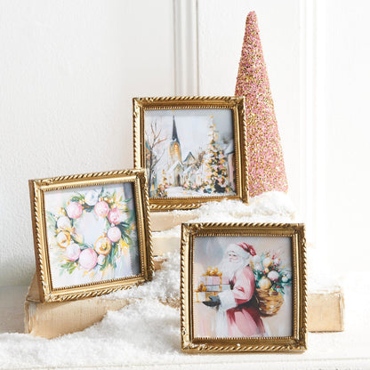 Twilight Tidings Mini Framed Christmas Wall Art, Three small square Christmas prints in ornate gold frames showing Santa carrying gifts, a wreath of pink and gold ornaments, and a snowy church scene.