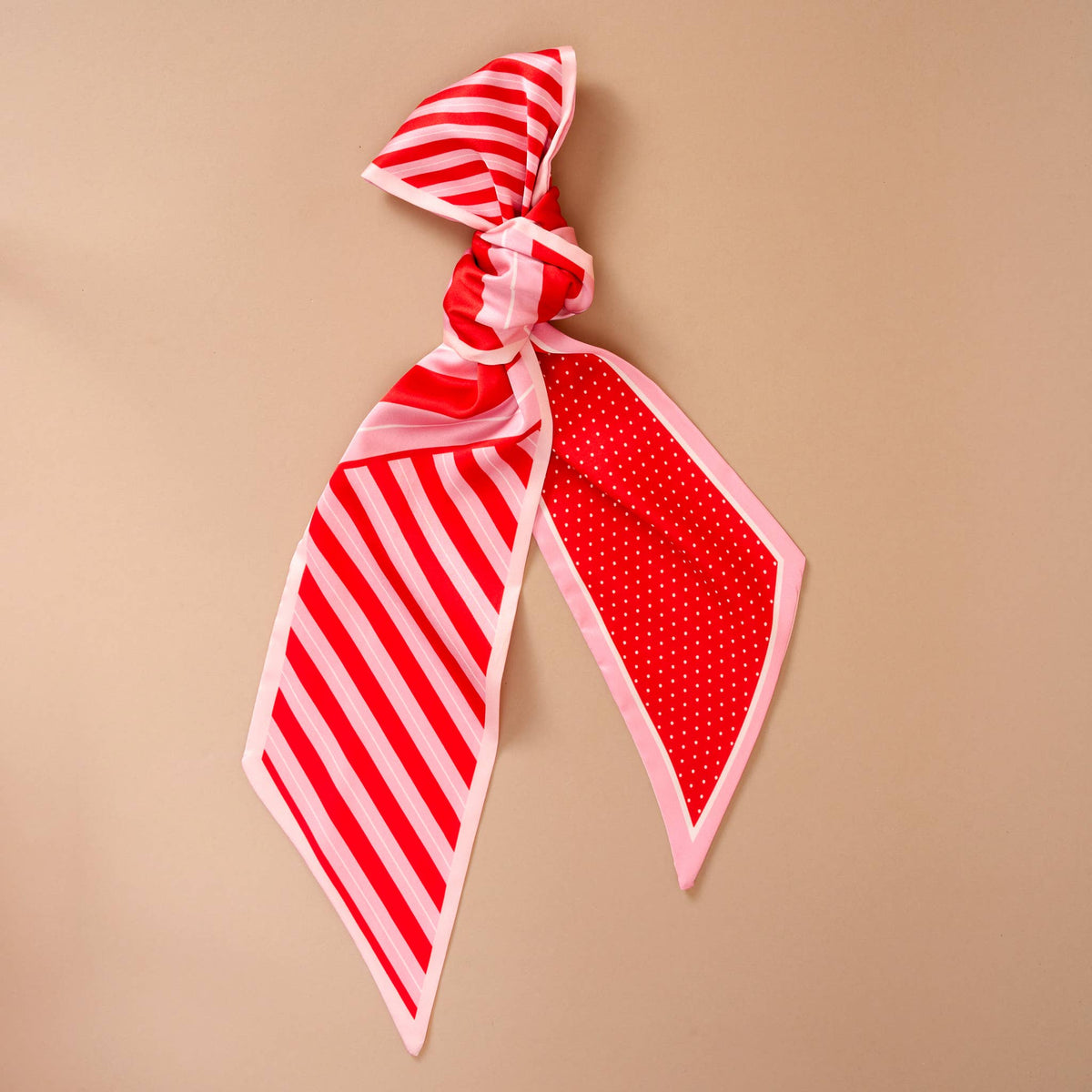 Twirl & Tie Scarf Accessory, A red and white gingham satin scarf tied in a knot, showing a red polka dot pattern on the reverse side of the tails.
