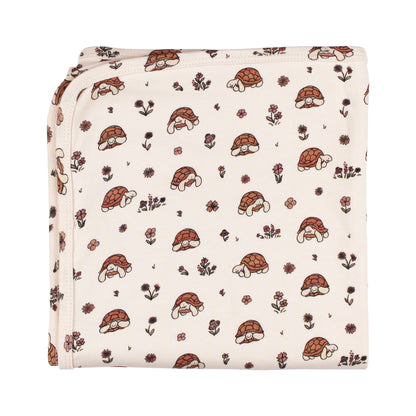 Organic Cotton Baby Blanket, Tiny Tortoise Print, A cream baby blanket folded to show a repeating print of tortoises with floral accents.