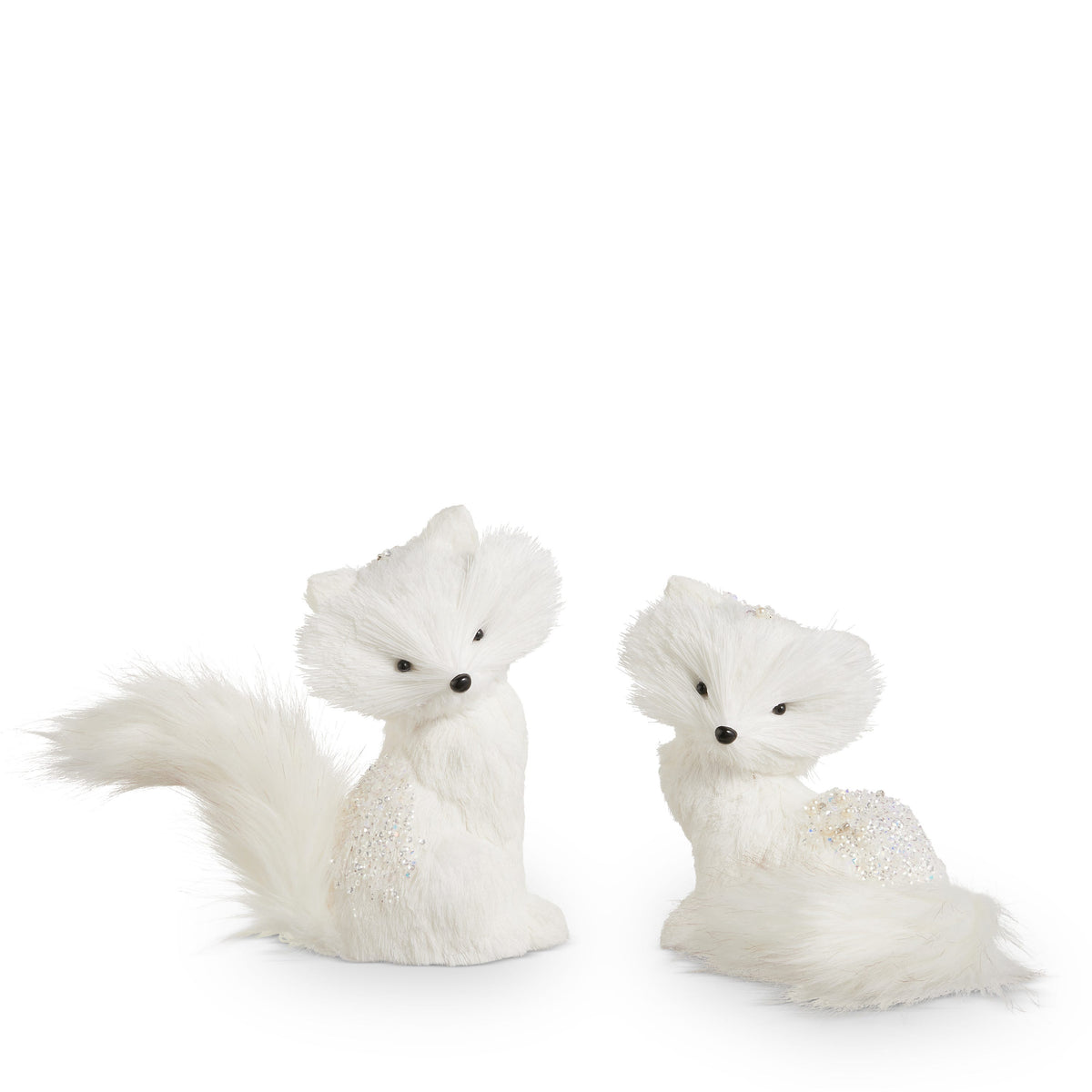 White Winter Fox Figurine, Two white faux fur fox figures with glittered backs, one sitting upright with a long tail and one resting with its tail curled around it.