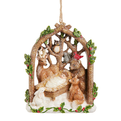 Woodland Nativity Ornament, A resin ornament shaped like an arched branch frame holding the Nativity manger scene surrounded by a deer, owl, fox, rabbit, bear, and cardinal, dusted with glitter snow.