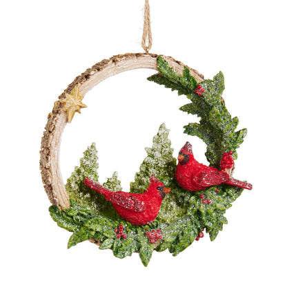 Woodland Noel Cardinals Ornament, A resin wreath ornament with two red cardinals, snow flocked pine boughs, holly berries, and a gold star, hanging from a jute cord.
